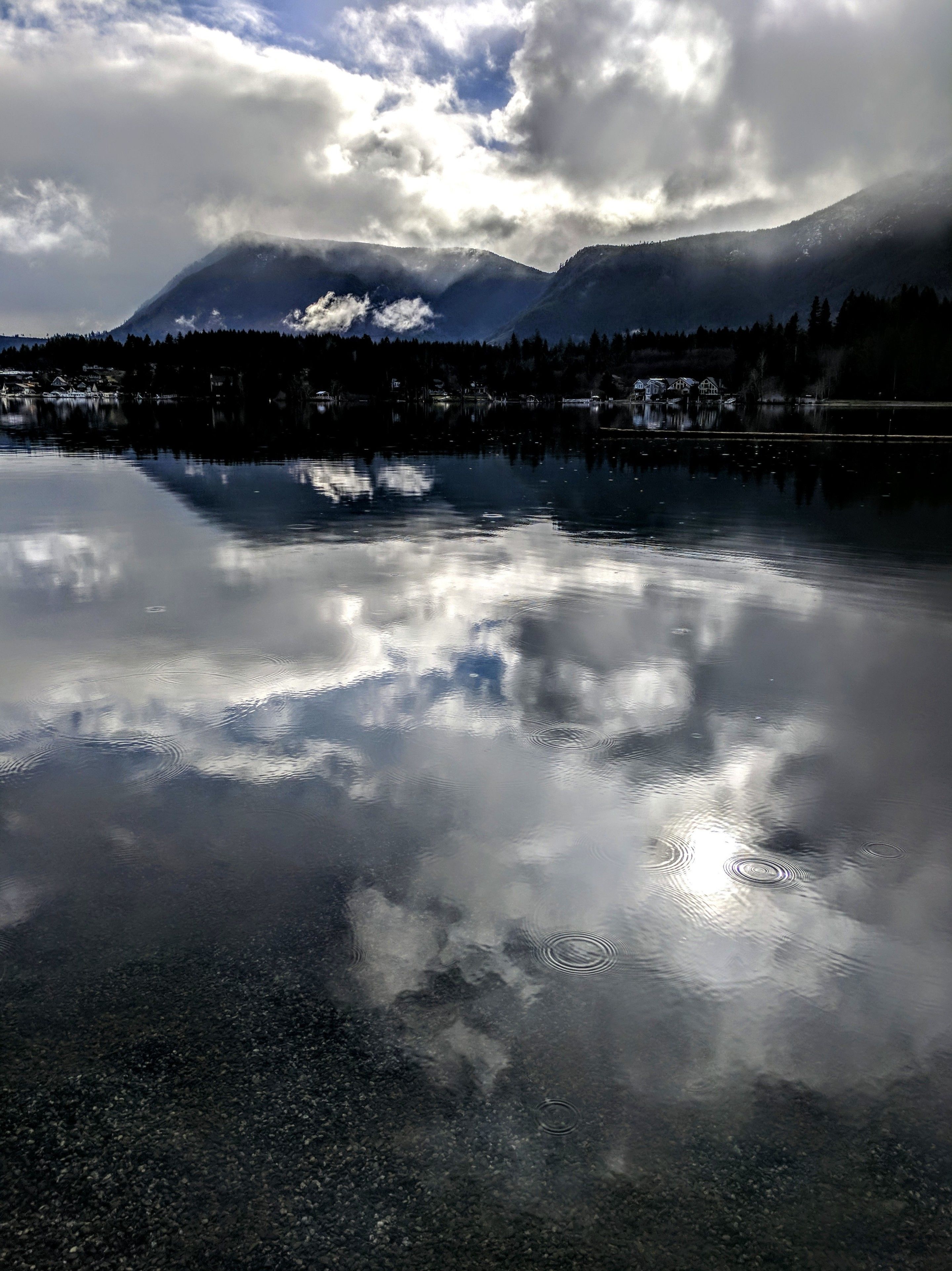 A calm lake reflecting clouds and mountains.