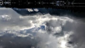 Un lago tranquilo que refleja nubes y montañas.
