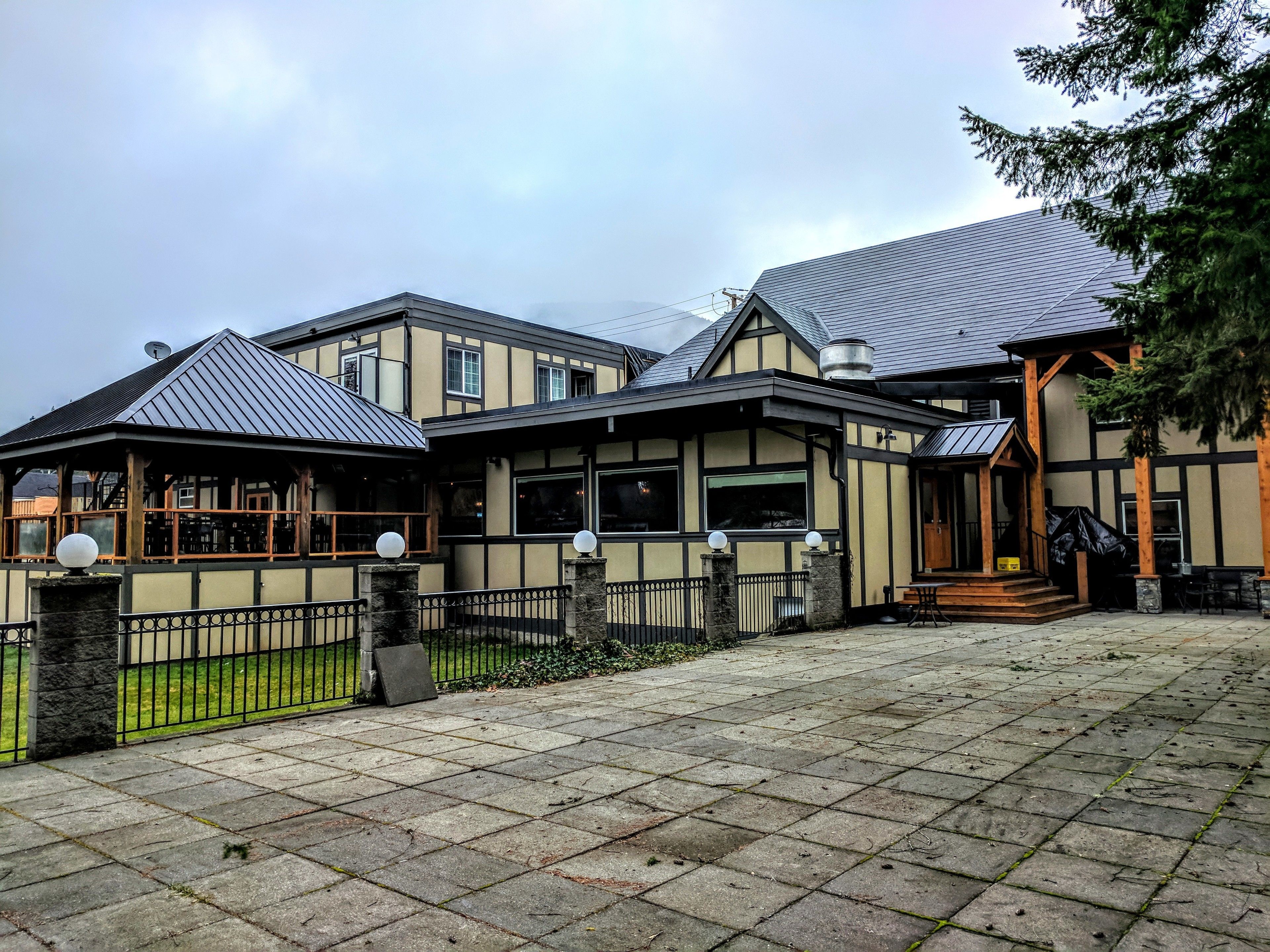 A traditional building with a covered patio area, stone pathway, and a fenced garden.