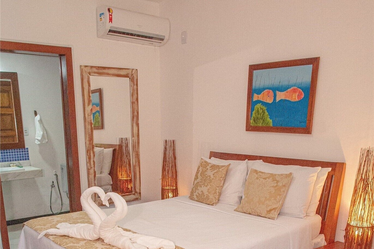 Ein Hotelzimmer mit Bett, Nachttisch, Spiegel, Klimaanlage und einem Bild an der Wand.