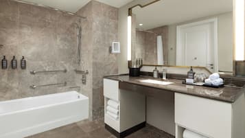 Un baño moderno con bañera, un espejo grande y tocador con artículos de aseo.