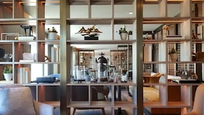 Uma sala de estar moderna com uma mesa de centro, rodeada por sofás e uma estante repleta de objetos decorativos.