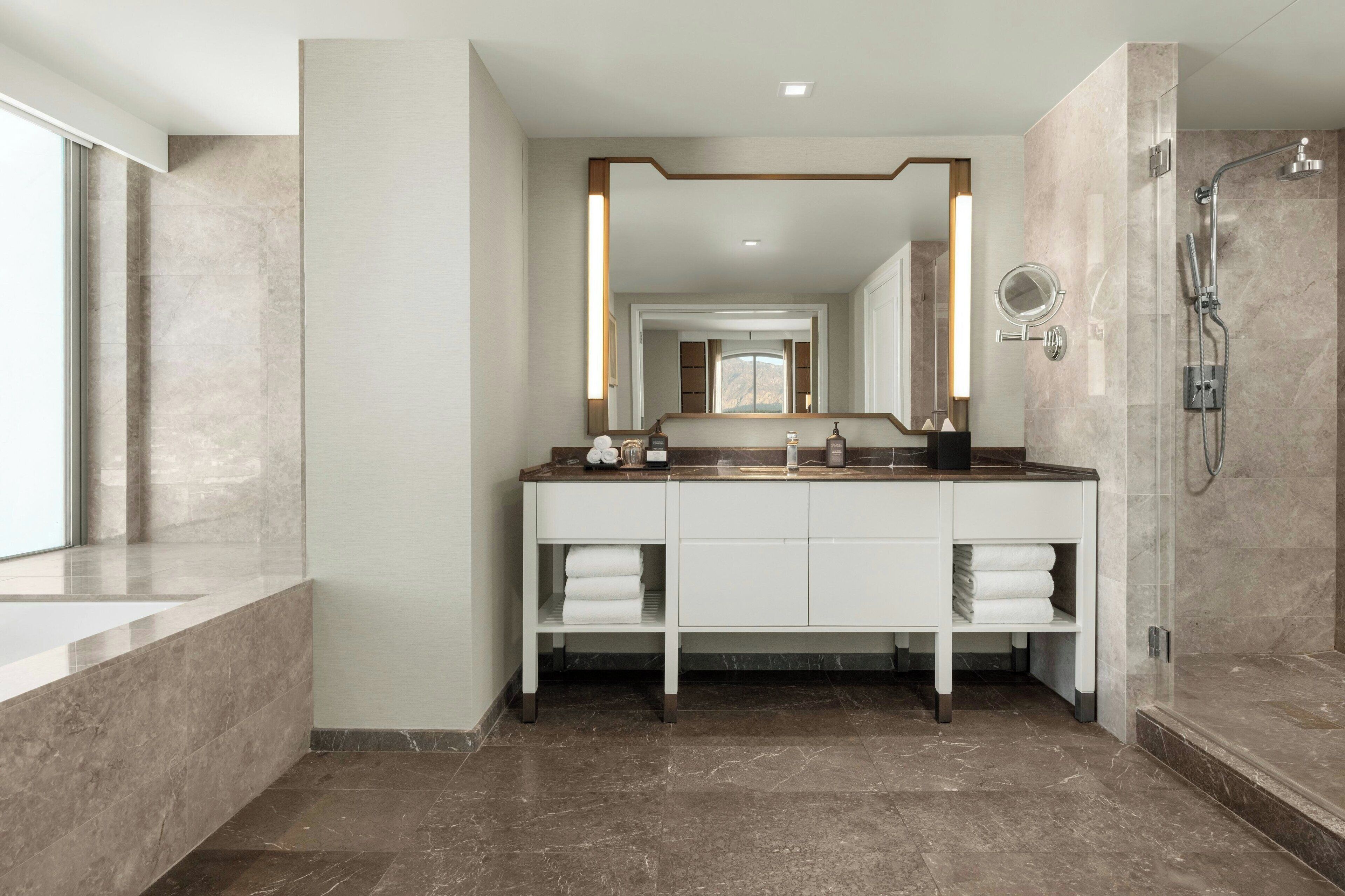 A modern bathroom with a double vanity, a large mirror, a shower, and a bathtub.