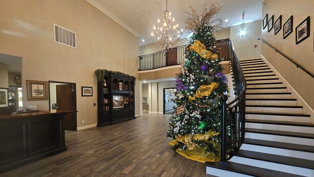 Un amplio vestíbulo con una imponente escalera, un árbol de Navidad y una mesa de recepción.