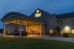 L’entrée d’un hôtel, avec une allée couverte et une voiture rouge garée devant.