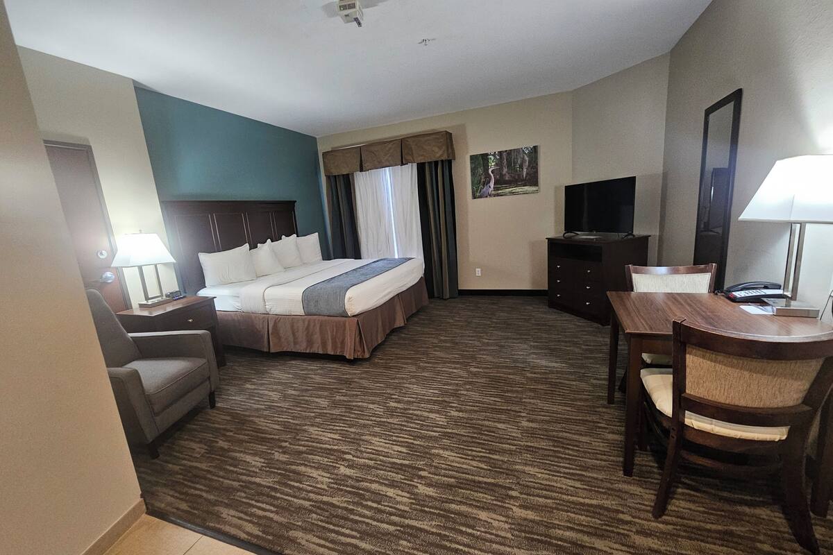 Une chambre d’hôtel avec un lit, un bureau, une chaise, une télévision et une lampe.