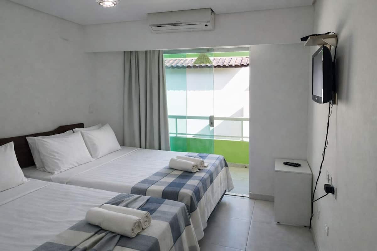 Une chambre d’hôtel avec deux lits, une télévision, un balcon et la climatisation.