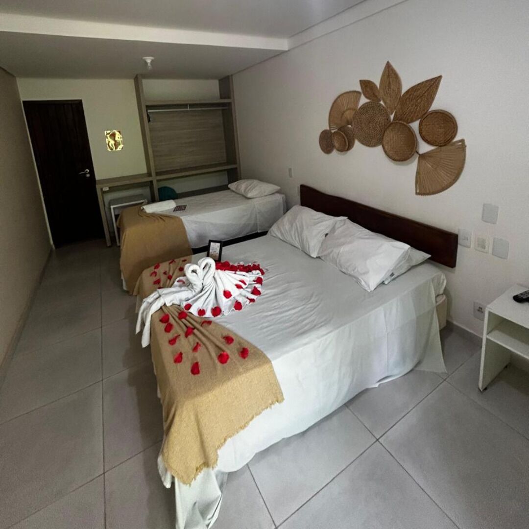 A hotel room with two beds, a small desk, and a wall decoration.