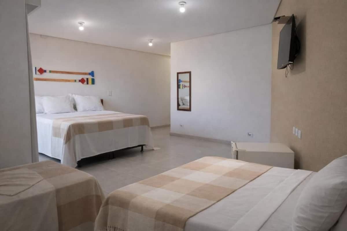 Une chambre d’hôtel avec deux lits, une télévision, une petite table et un tableau accroché au mur.