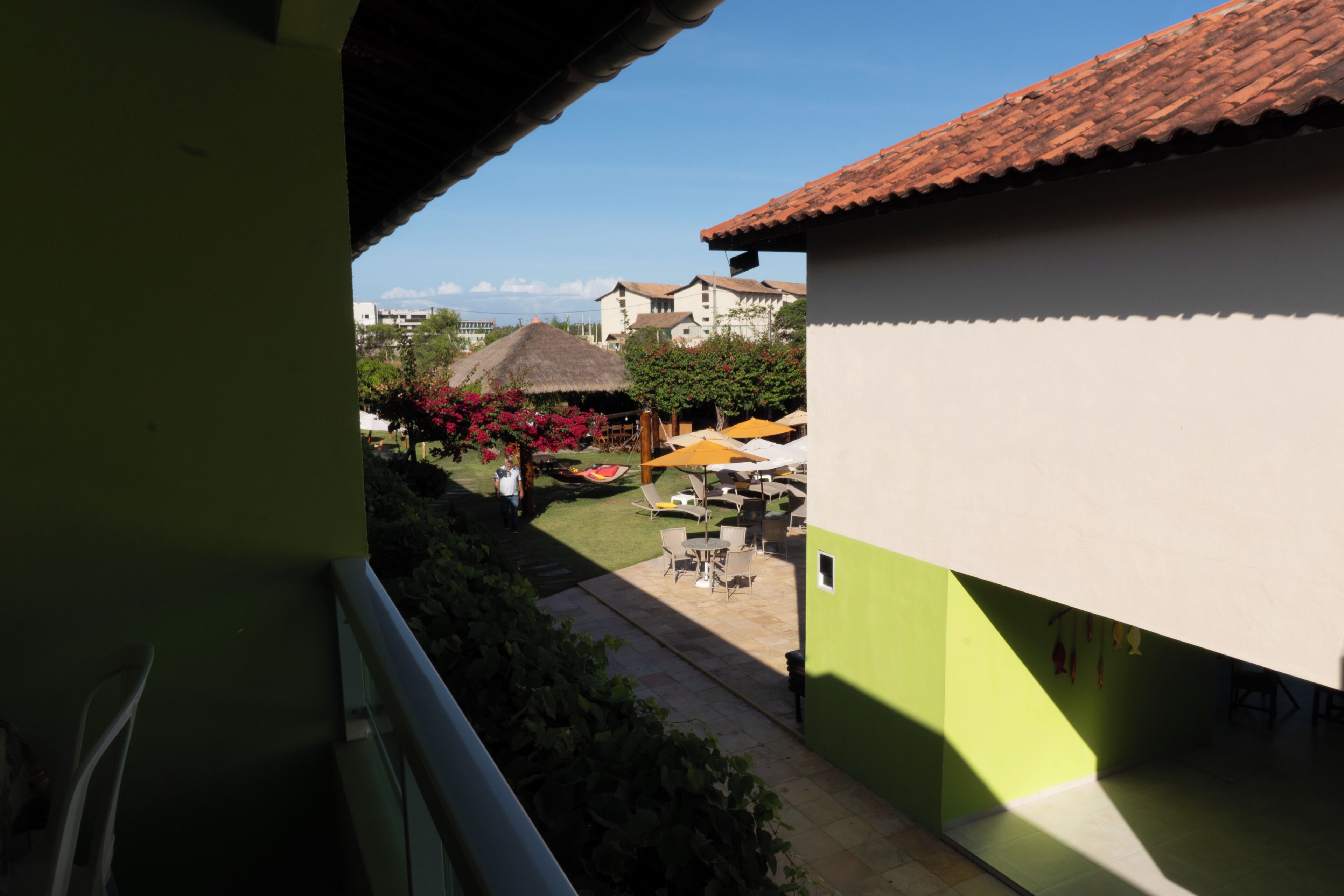 A courtyard with outdoor seating, a thatched-roof structure, and buildings with a tiled roof.