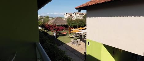 A courtyard with outdoor seating, a thatched-roof structure, and buildings with a tiled roof.