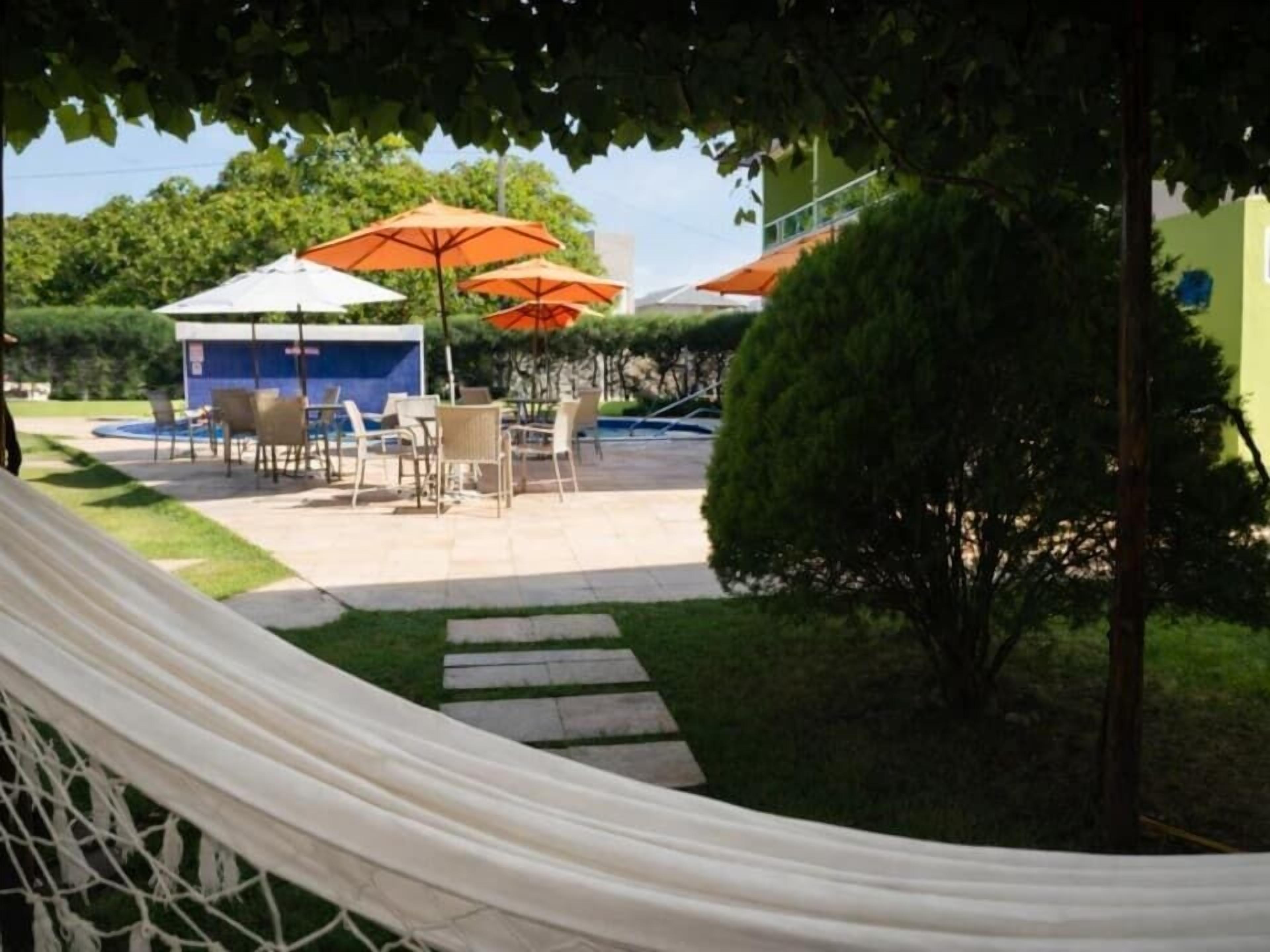 A patio area with outdoor furniture, umbrellas, and a pool.