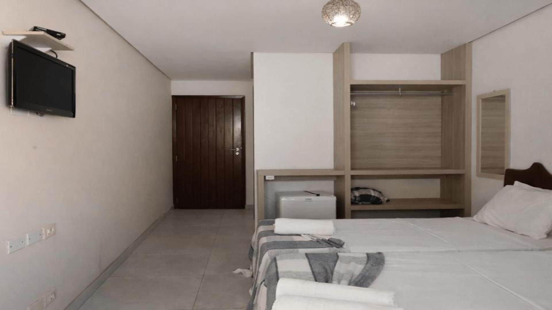 A hotel room with a bed, a wardrobe, a television, and a small desk.