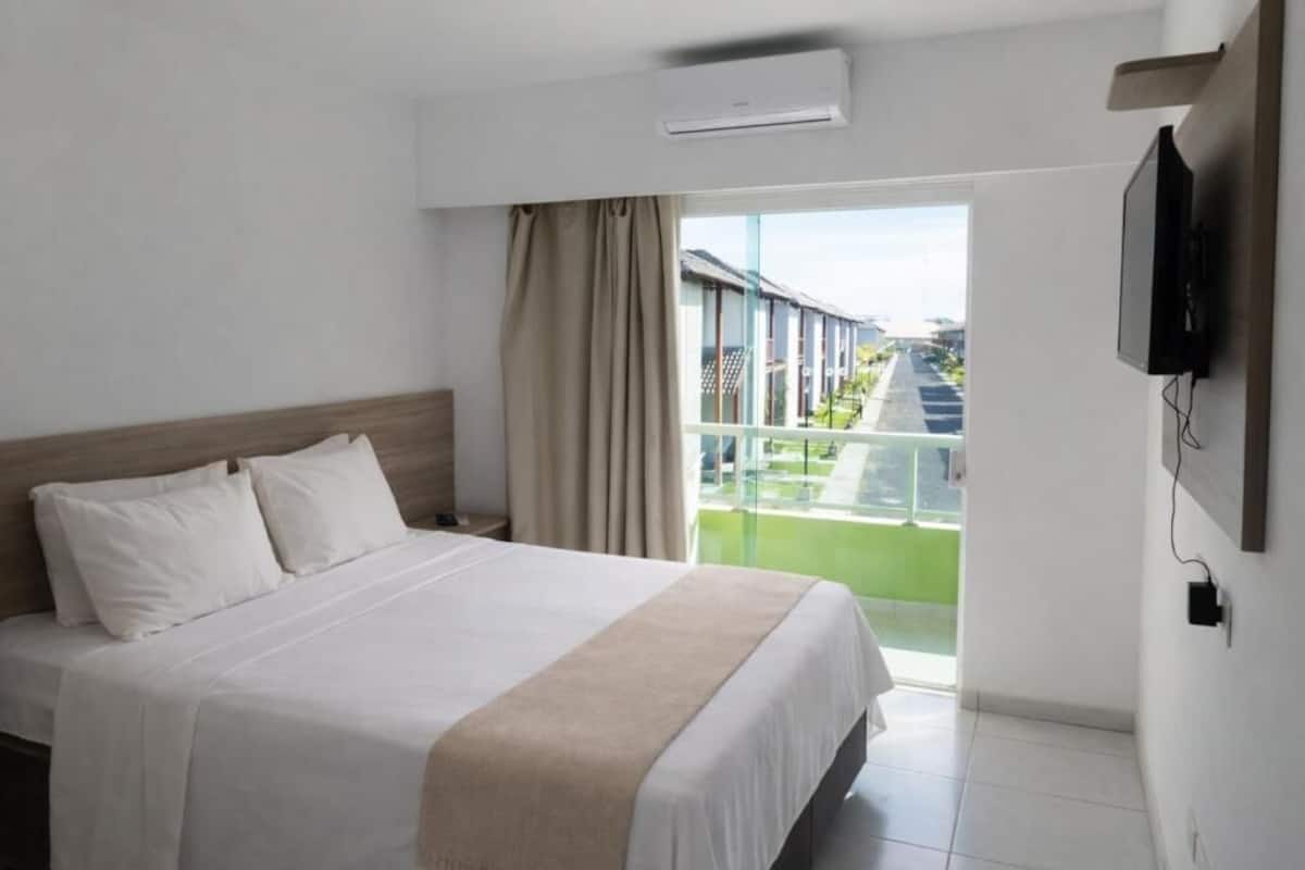Une chambre d’hôtel avec un lit, une télévision et une vue sur un immeuble par la fenêtre.