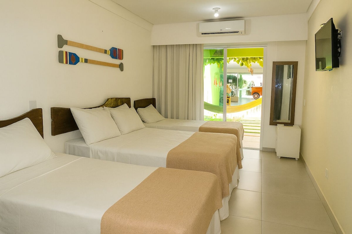Une chambre d’hôtel avec trois lits, une télévision, un appareil de climatisation et une vue sur un terrain de jeux.