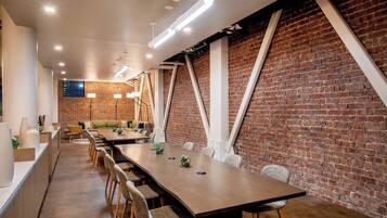 A conference room with a long table, chairs, and a brick wall.