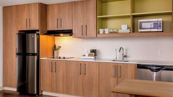 A modern kitchen with wooden cabinets, stainless steel appliances, and a built-in microwave.