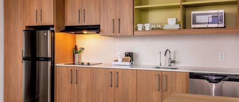 A modern kitchen with wooden cabinets, stainless steel appliances, and a built-in microwave.
