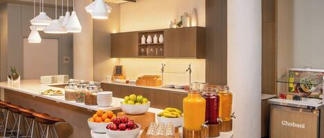 A modern kitchen with a central island stocked with fruits, beverages, and condiments.