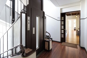 A staircase with a handrail, a door with a handle, and a mat at the bottom. - Feel Porto Downtown Townhouses (Porto)