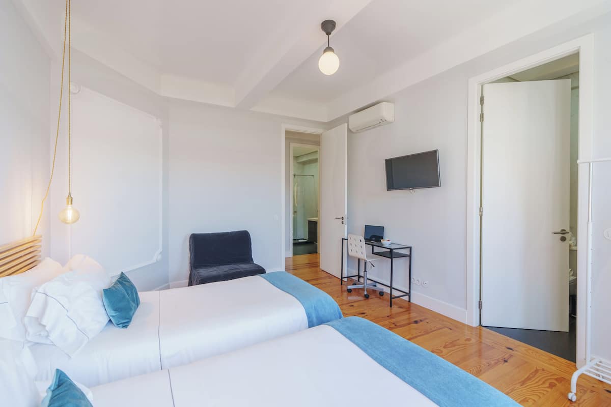 Ein modernes Schlafzimmer mit Bett, Schreibtisch und Fernseher.