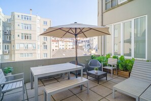 A balcony with a table, chairs, an umbrella, and potted plants. - Feel Porto Downtown Townhouses (Porto)