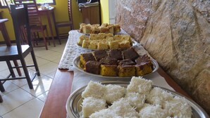 A dining table with various desserts and a plate of coconut shreds. - Pousada Casa do Mar (Paraty)