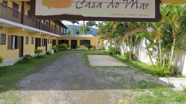 A building with a sign reading "Casa do Mar" and a view of the surrounding area including a pathway and greenery. - Pousada Casa do Mar (Paraty)