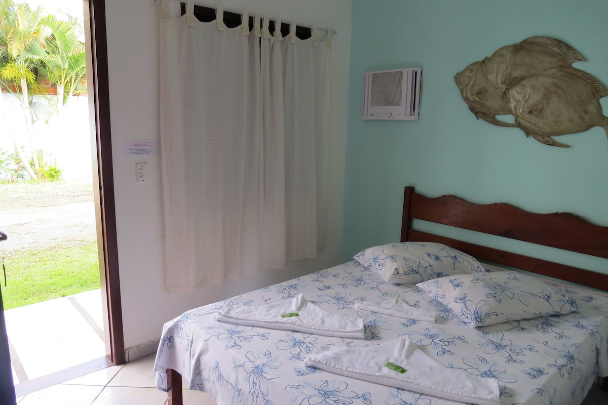 Ein Schlafzimmer mit einem Bett, einem Vorhang, einer wandmontierten Klimaanlage und einem Wandbild mit einem Fisch.