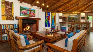 Una zona de estar acogedora con muebles de madera, chimenea y obras de arte en las paredes.