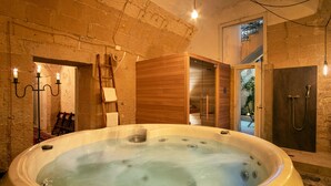 A hot tub in a rustic room with stone walls, a wooden door, and a ladder. - Palazzo Guido Boutique Hotel (Lecce)