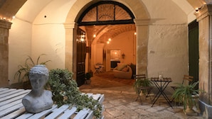 An arched doorway leading to a cozy interior space with a dining area, a sofa, and potted plants. - Palazzo Guido Boutique Hotel (Lecce)