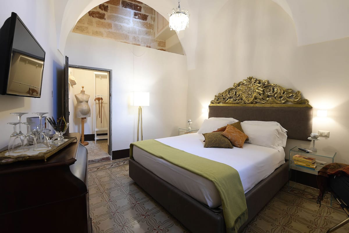 Un dormitorio con una cama grande, un aparador, un tocador y una araña.