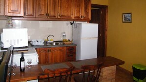 A kitchen with wooden cabinets, a white refrigerator, a sink, and a dining area with chairs. - SAN JOSÉ RURAL HOUSE  (Yaco)