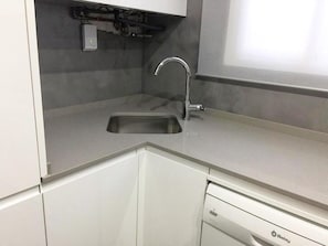 Efficient kitchen with a stainless steel sink, dishwasher, and white cabinetry.