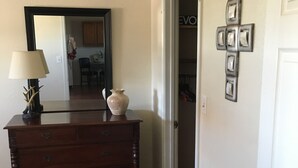 A wooden dresser with drawers, a vase, and a lamp in a hallway with a wooden floor. - Tumble Weed Cabin of Lonesome Wind Ranch (Floresville)
