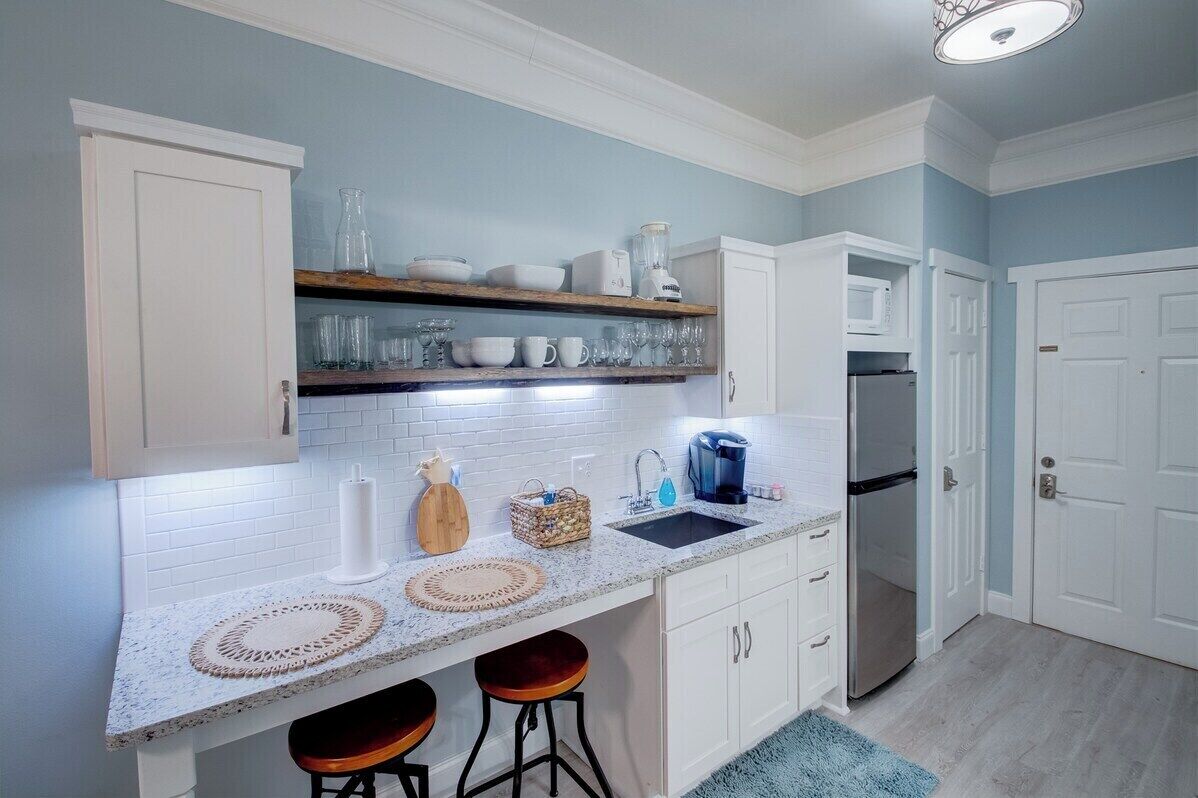 A kitchen with white cabinets, a granite countertop, a built-in oven, and a refrigerator.