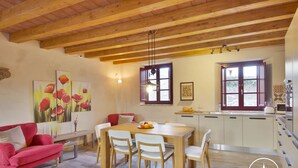 Un coin repas avec une table et des chaises en bois, un canapé rouge et des œuvres d’art accrochées aux murs.