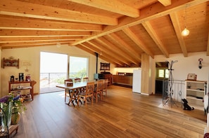 A spacious living area with a wooden floor, a dining table, and a kitchen in the background. - BELLAGIO LES ETOILES villa with garden, hot tube, lake view, bbq, private parking (Bellagio)