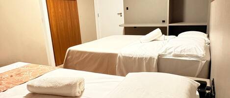 A hotel room with two beds, a TV mounted on the wall, and a wardrobe.
