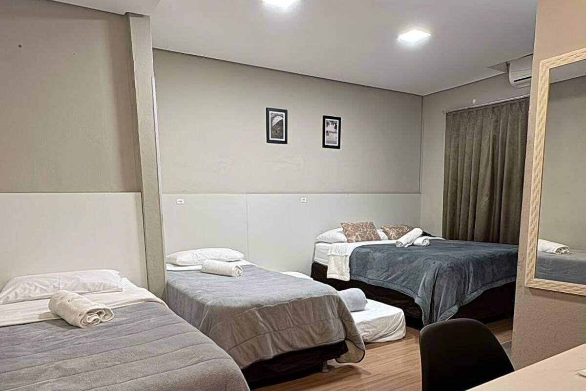 A hotel room with three beds, a desk, and a mirror.