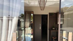 Un ingresso moderno con porte in vetro, un pavimento riflettente e un lampadario.