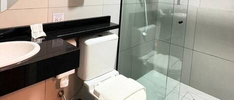 A modern bathroom with a glass-enclosed shower, a white toilet, and a black countertop with a sink.