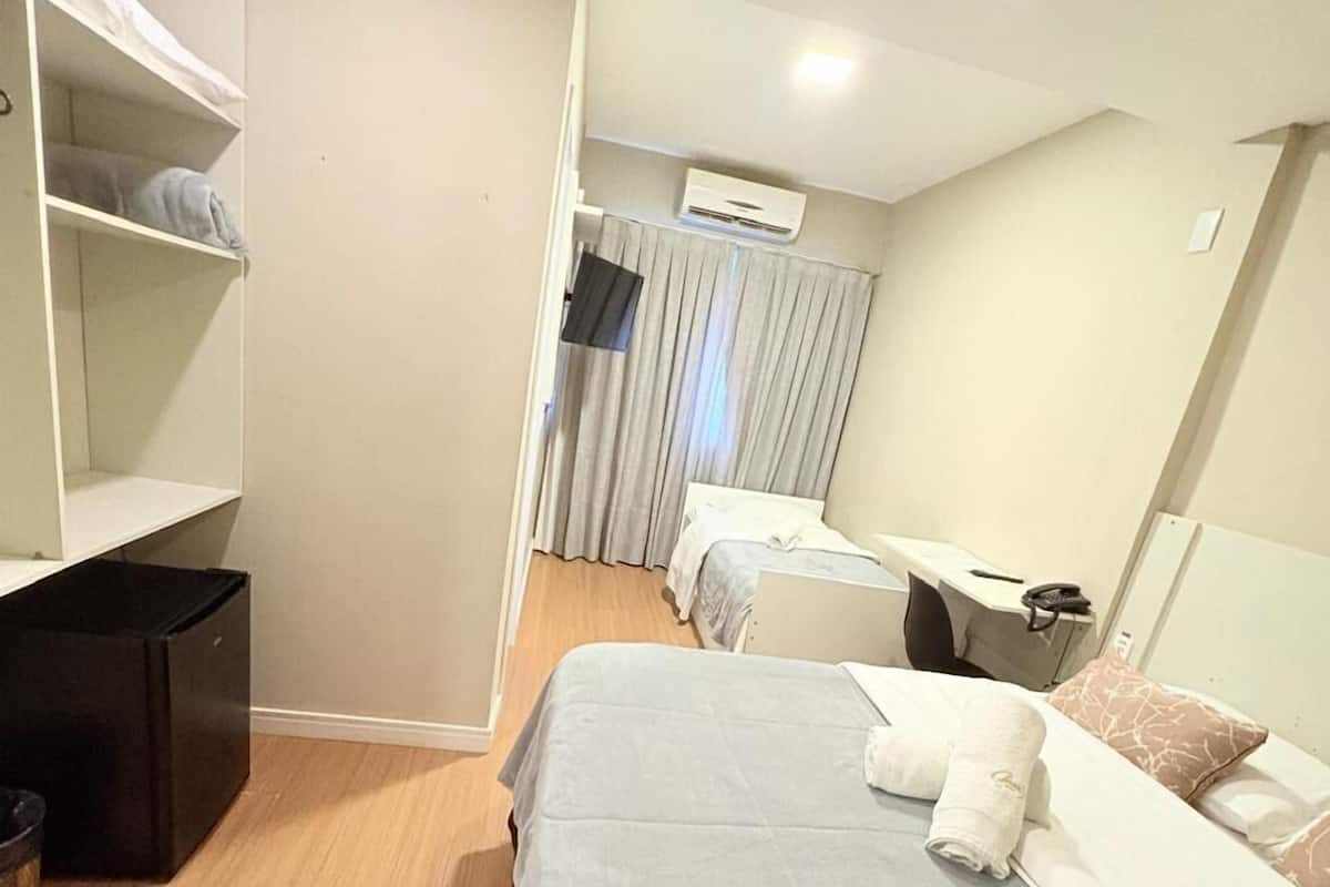 A hotel room with a large bed, a desk, a wardrobe, and a TV.