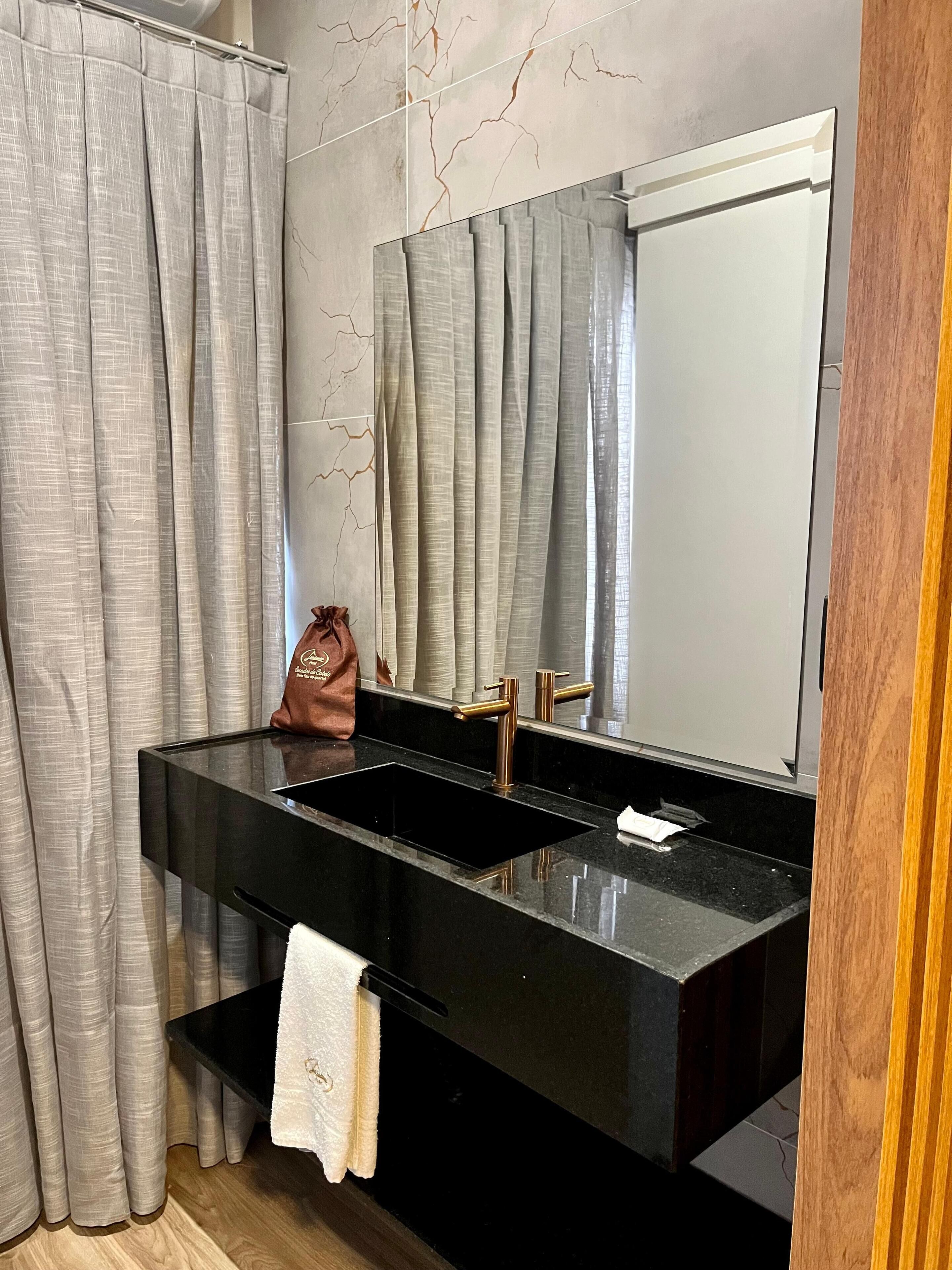 Une salle de bain moderne avec un lavabo noir, un porte-serviettes et un miroir.
