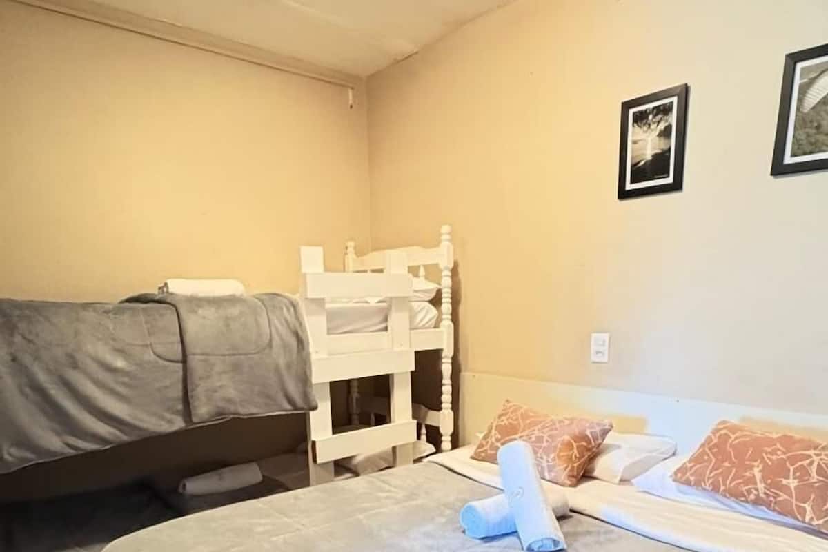 A room with a bed, a sofa, a small table, and a wall-mounted shelf.