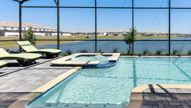 Un espace piscine comprenant un jacuzzi, des chaises longues et une vue sur un lac.