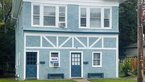 Uma casa de dois andares com fachada azul, detalhes brancos e uma chaminé.