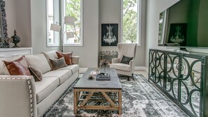 Un salon moderne comprenant un canapé, un fauteuil, une table basse et un téléviseur.