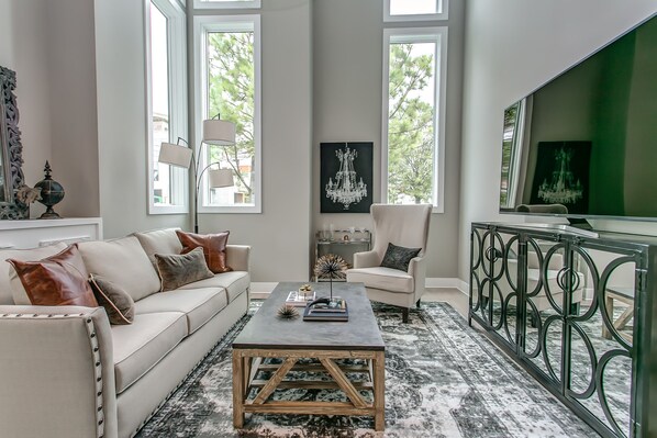 A modern living room with a sofa, armchair, coffee table, and a TV.